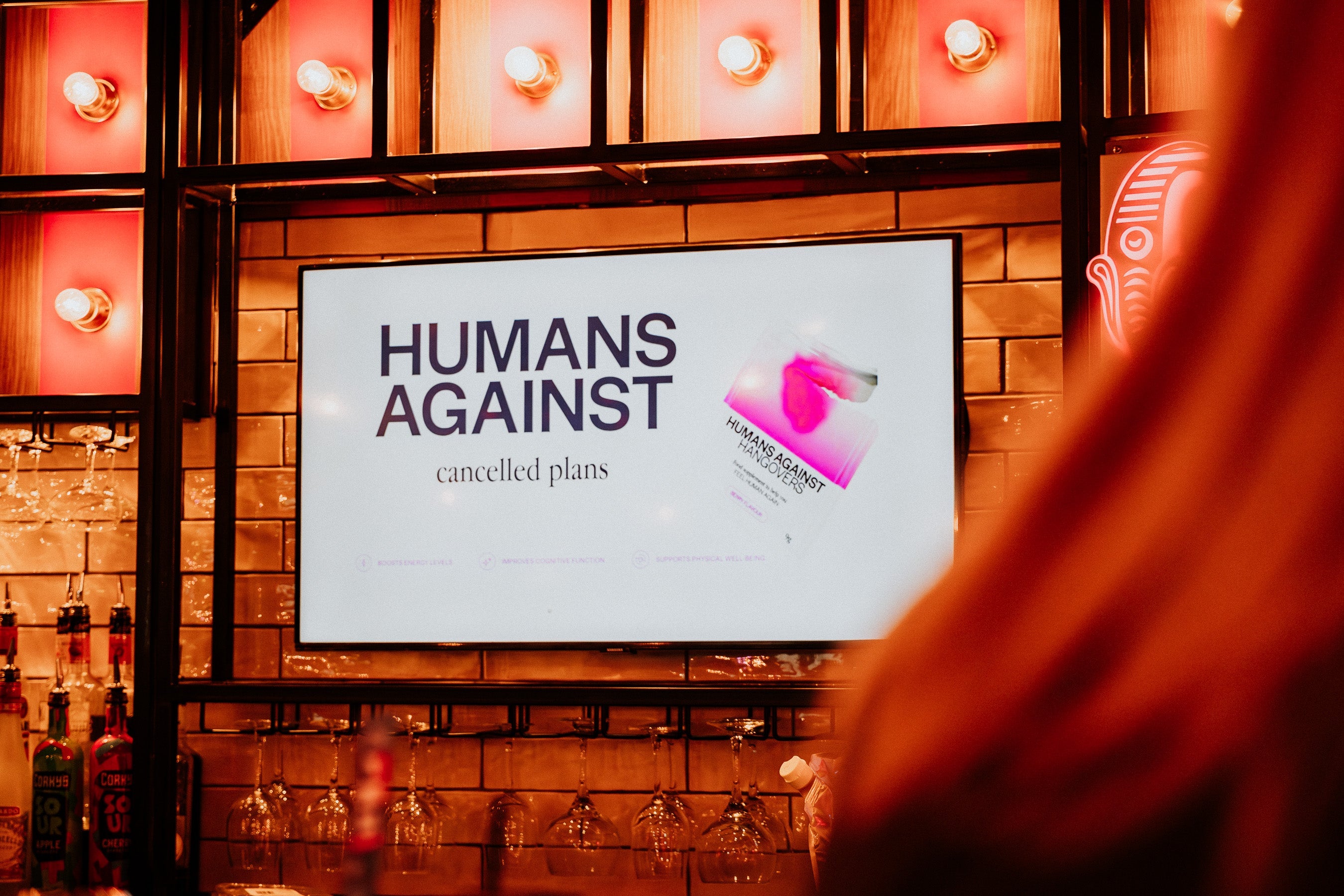 A TV screen in a bar with a Humans Against Hangovers logo on screen